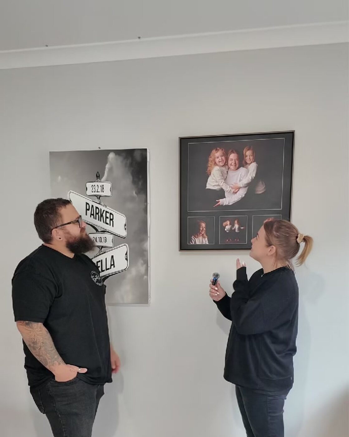 A couple looking up at their framed family portrait hanging in their home