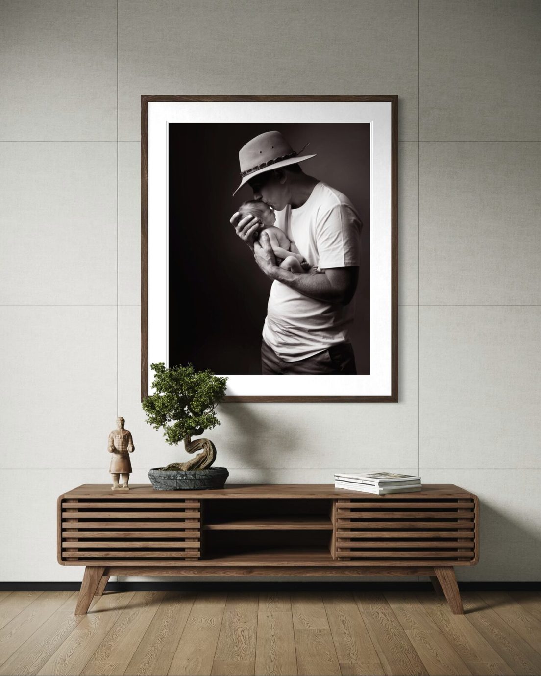 Black and white framed portrait of a father and newborn above a timber cabinet