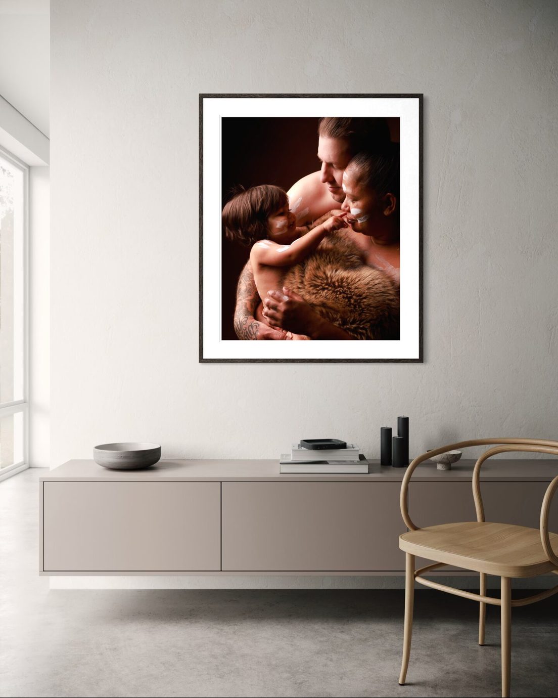 Framed portrait hanging above a low sideboard in a bright living room