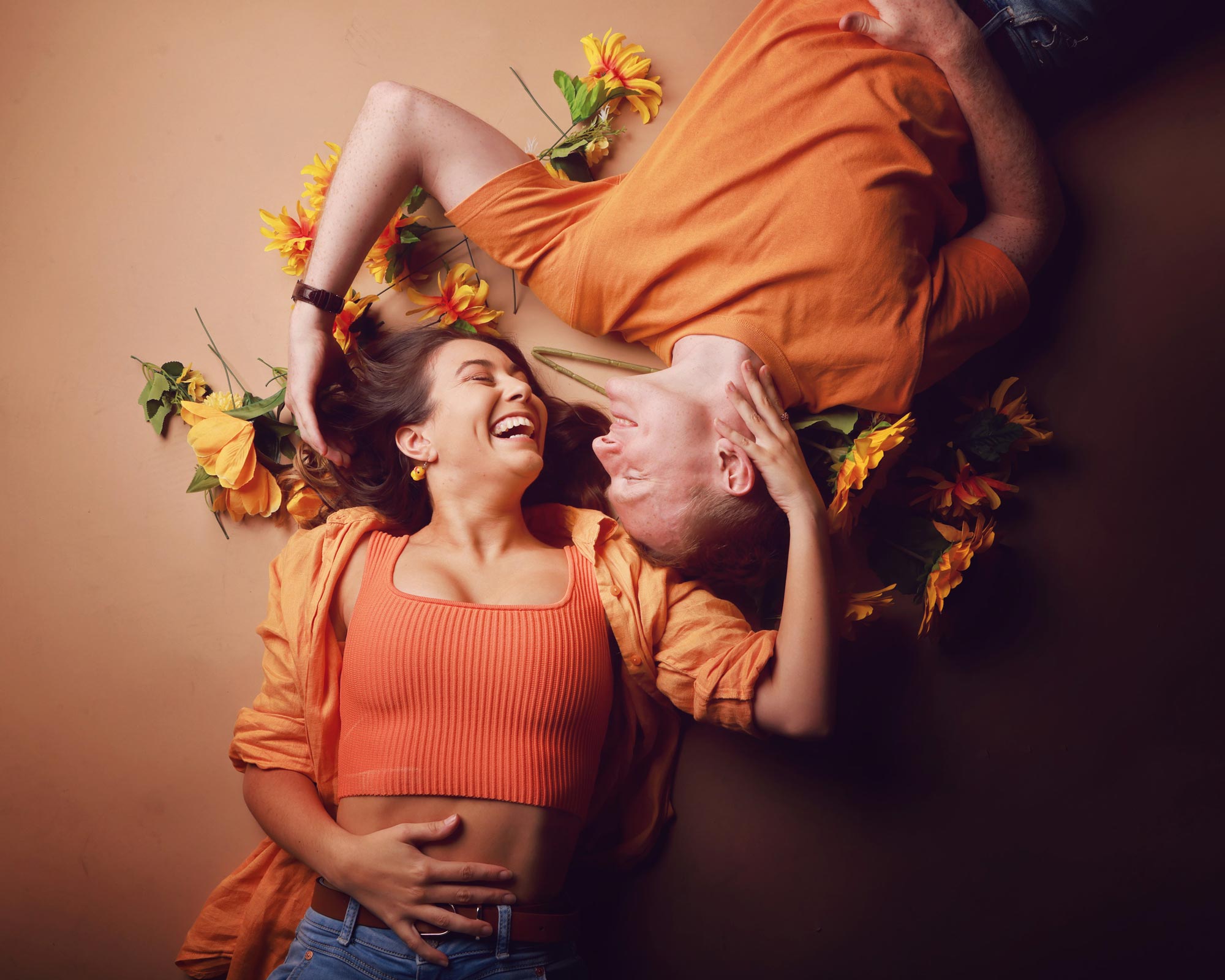 A couple lying down among sunflowers, laughing together